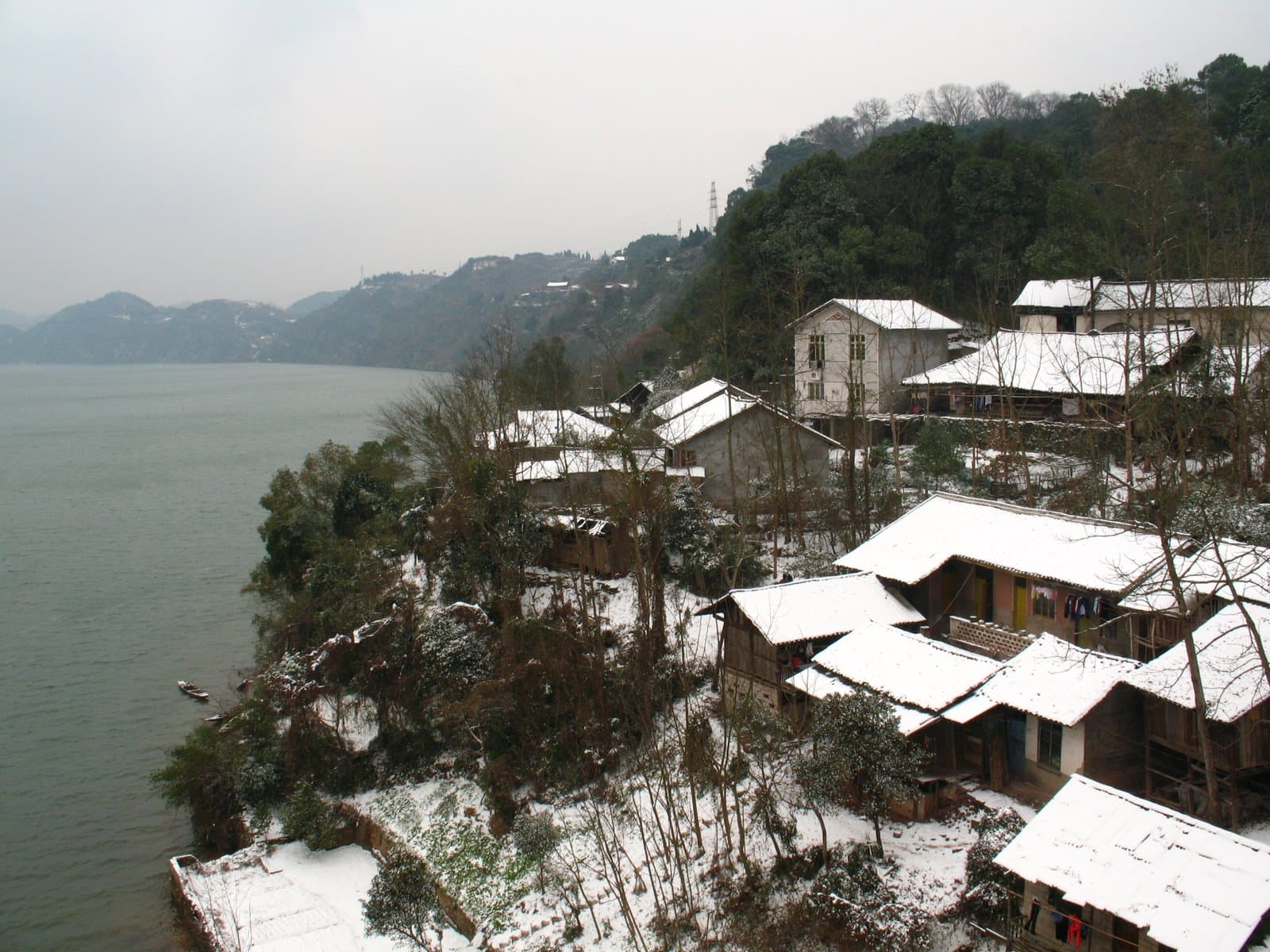 Snow-covered houses on a hillside overlooking a lake