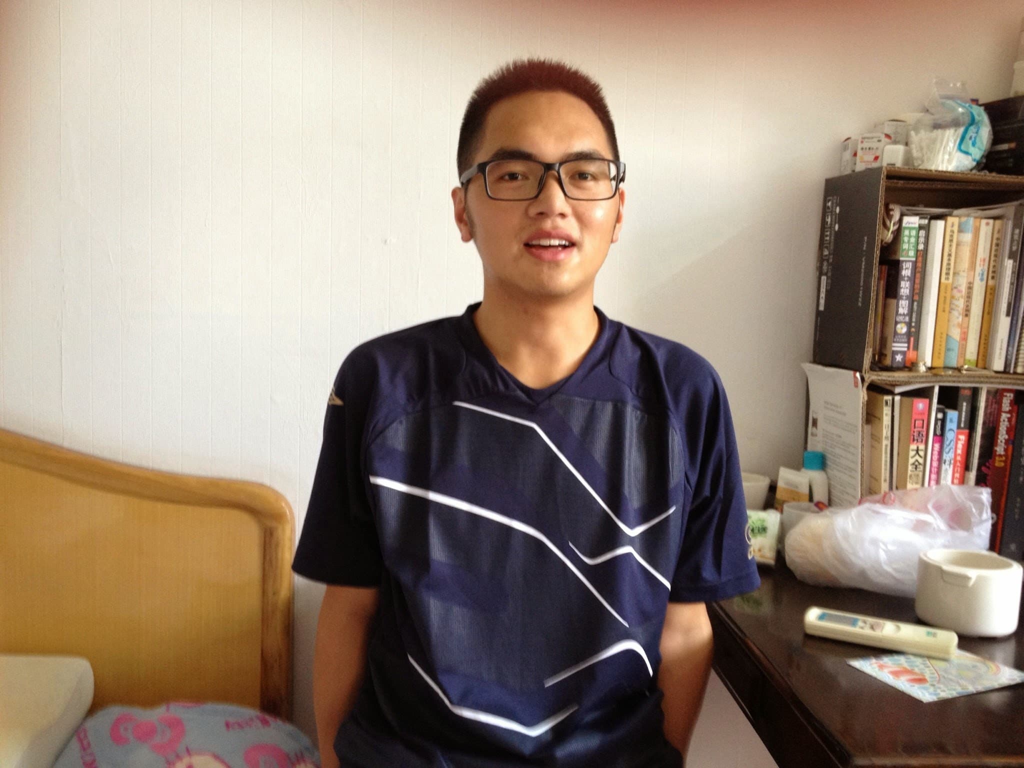 A young man wearing glasses standing in a room