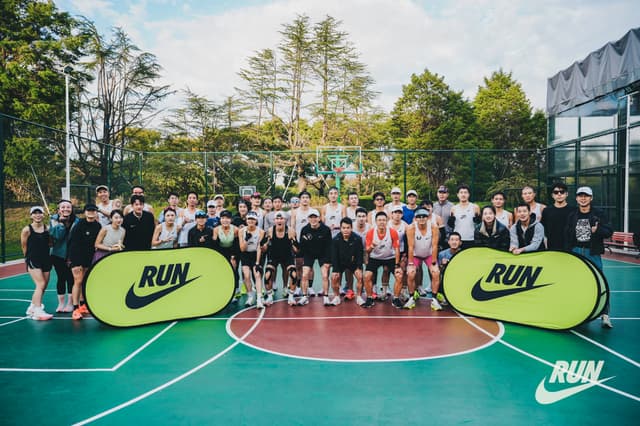 a large group of people standing on a tennis court with Nike promotional banners