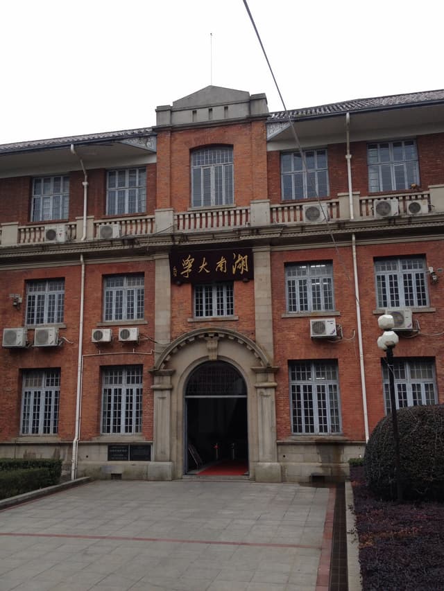 A red brick building with multiple windows and a balcony