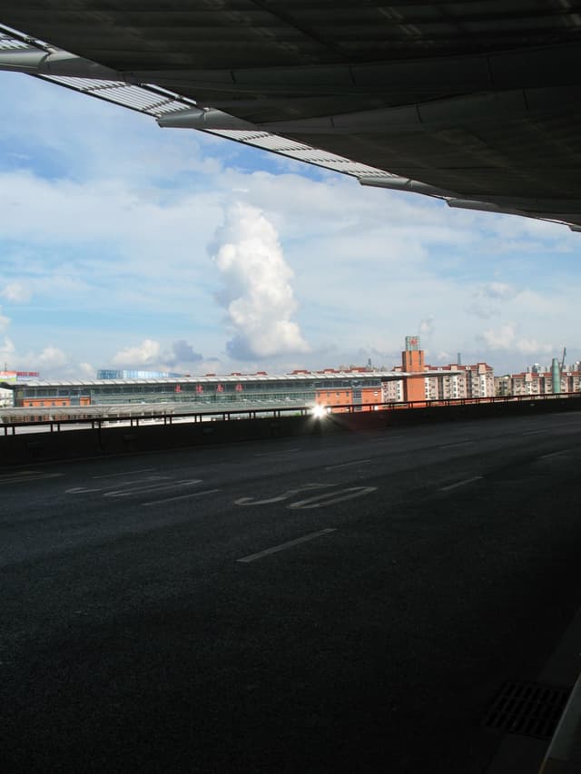 A city bridge with buildings in the background under a blue cloudy sky