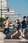 three runners jogging on a city street sidewalk
