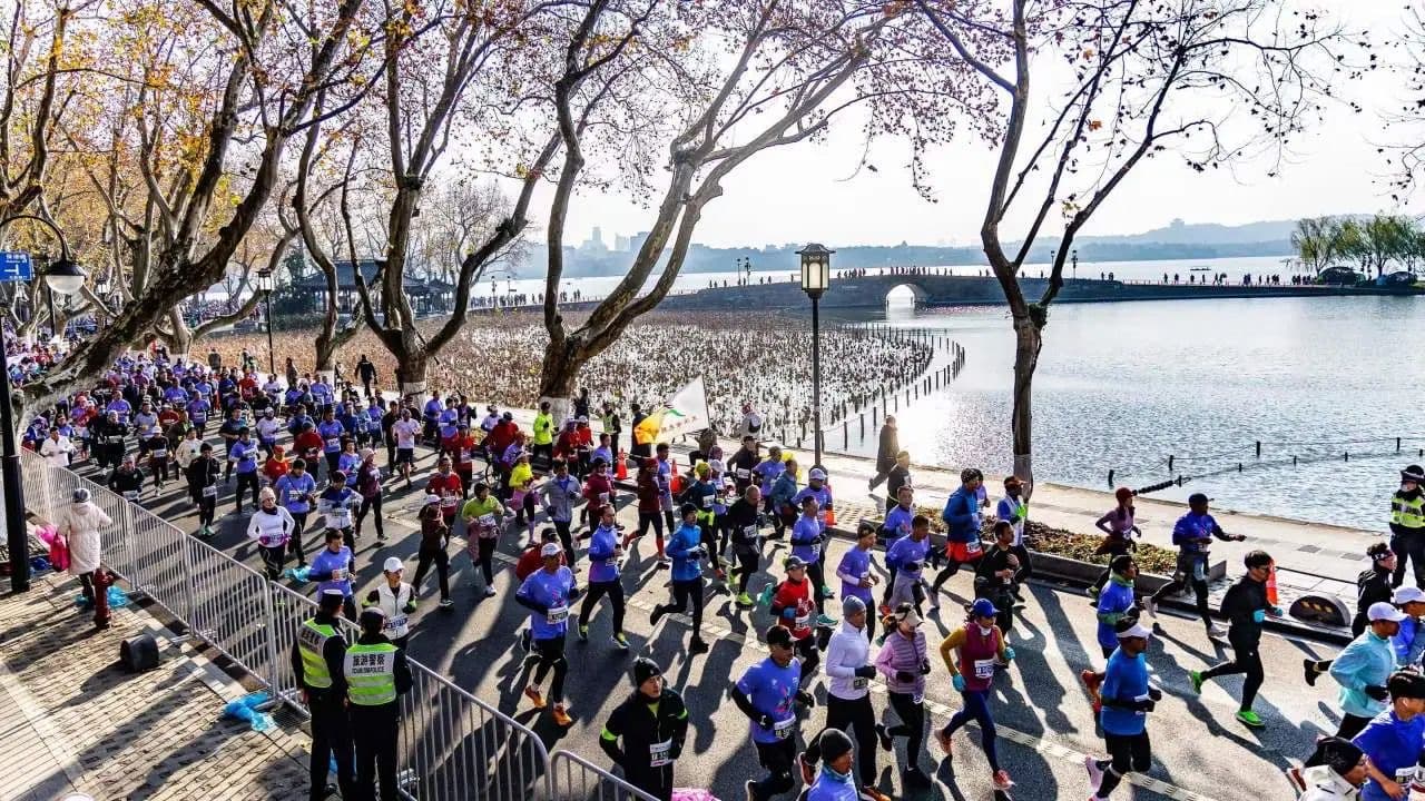 a large group of runners on a path near a body of water
