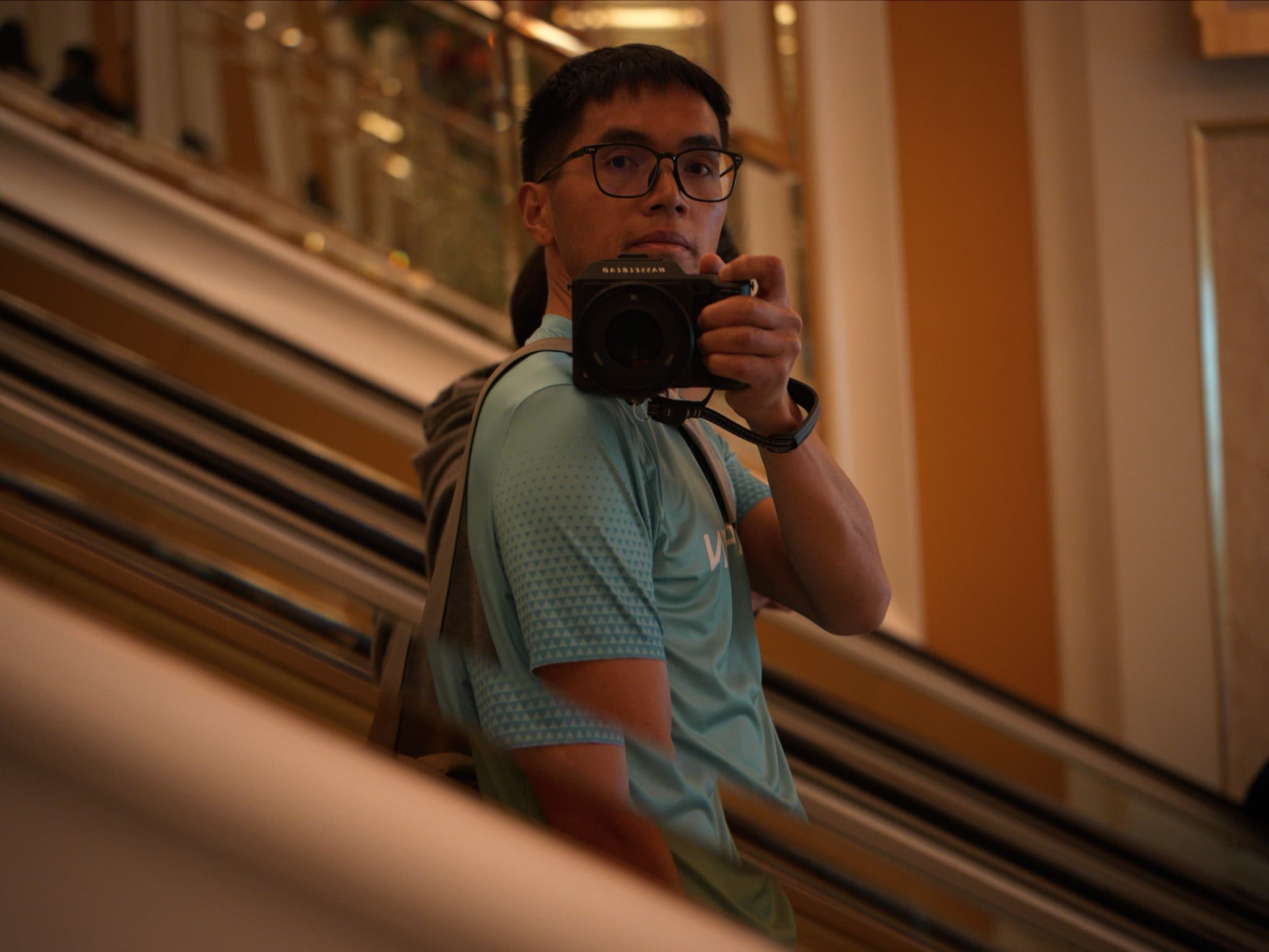 Man riding an escalator with a camera