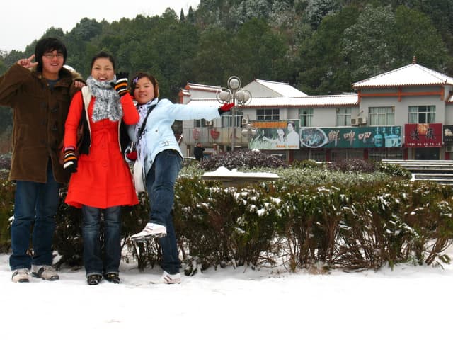 A family of three posing in the snow with a snowy landscape and buildings in the background