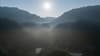 sun shining through fog over mountains