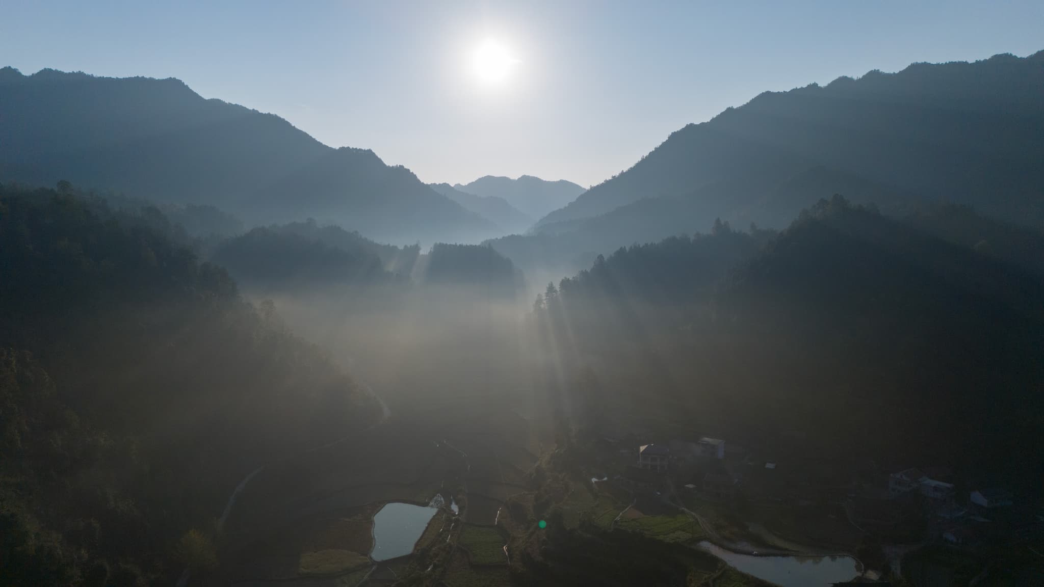 sun shining through fog over mountains