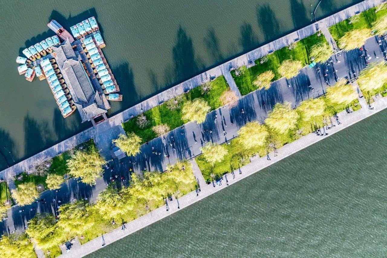 aerial view of a waterfront promenade with trees and a building