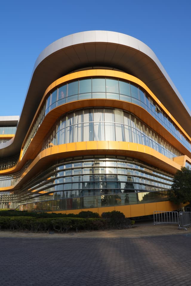 A modern curved building with yellow accents and large glass windows