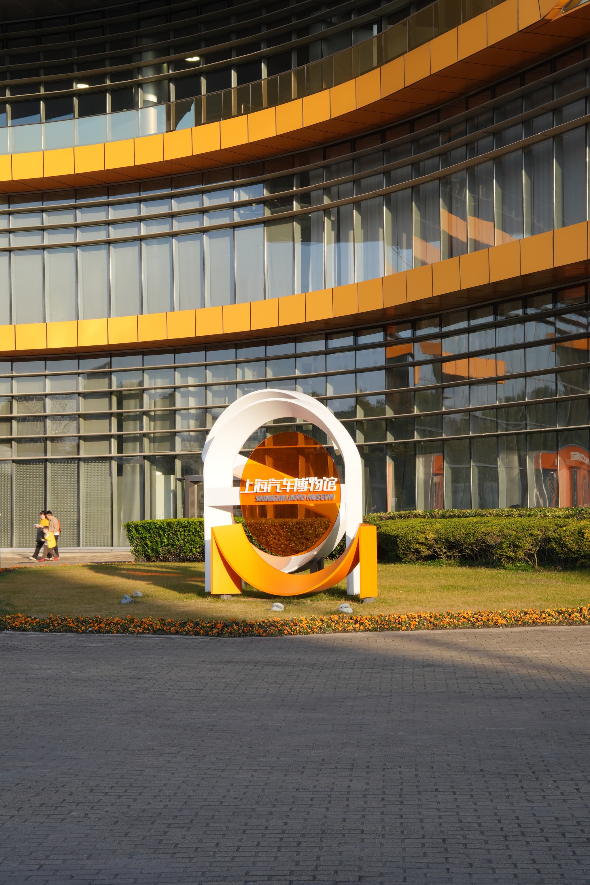 A modern, multi-level building with a unique circular sculpture in front