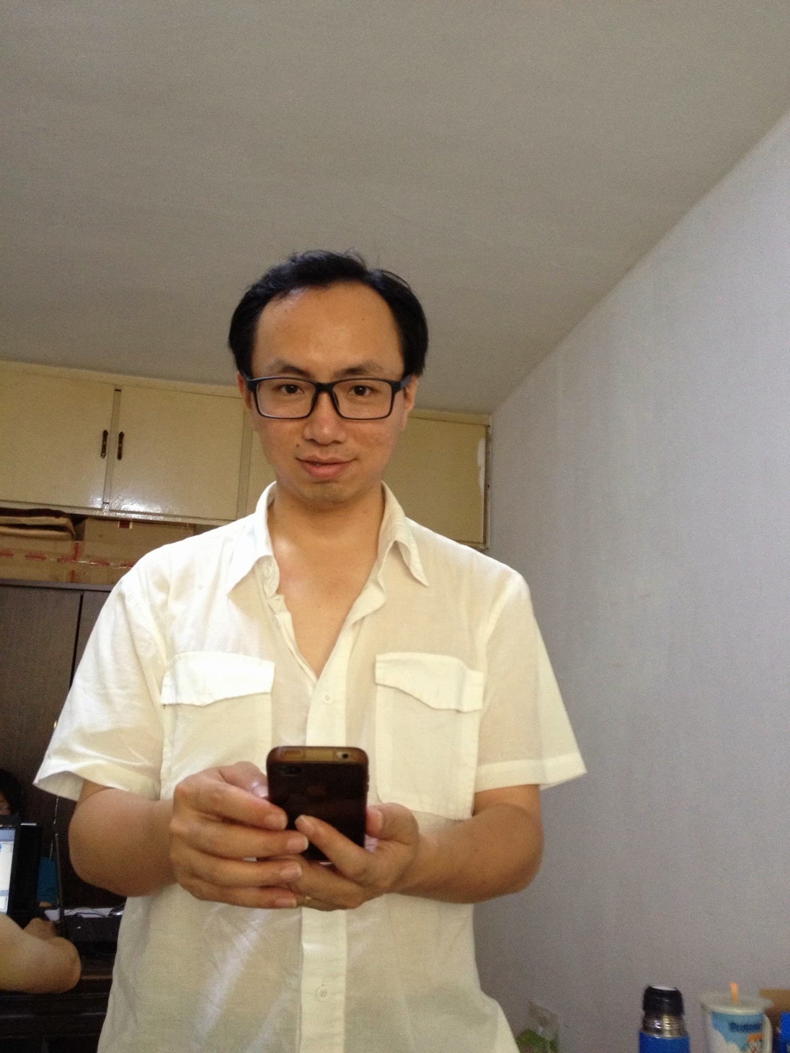 Man standing in kitchen holding phone