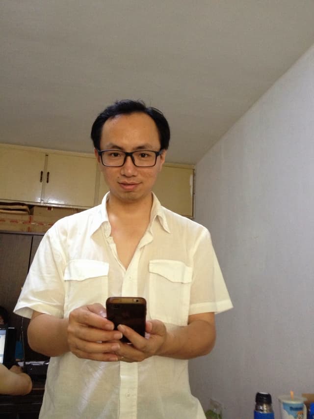 Man standing in kitchen holding phone