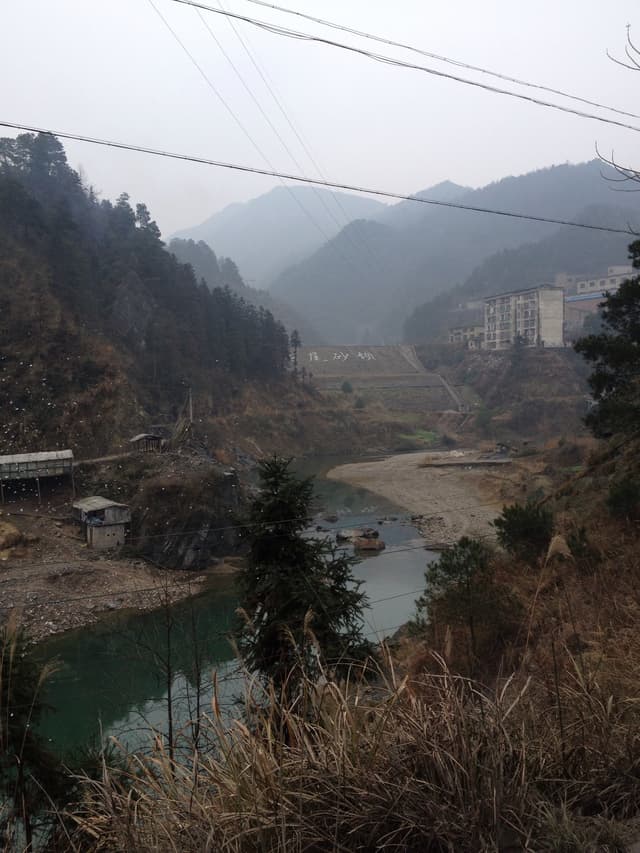 A serene mountain lake surrounded by trees and hills on a cloudy day