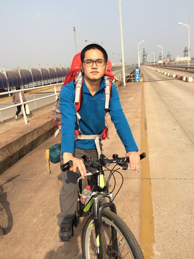 Man posing on a bicycle on a bridge