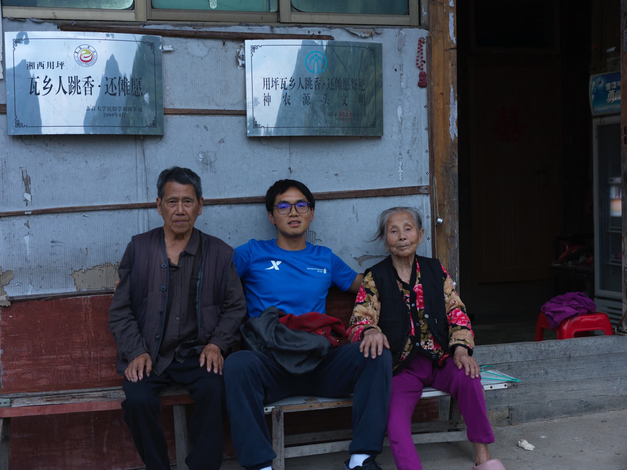 Three people sitting on a bench outside a building