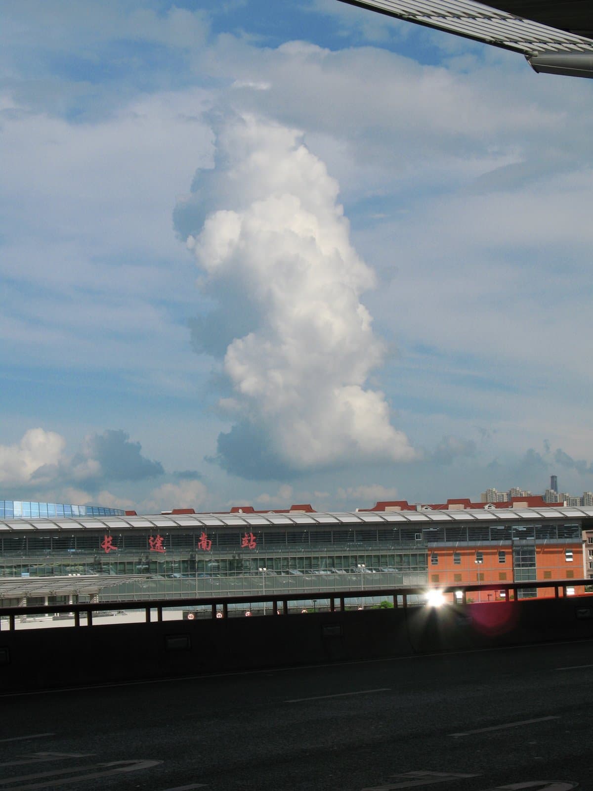 A large cloud formation over a cityscape with a body of water and buildings in the foreground
