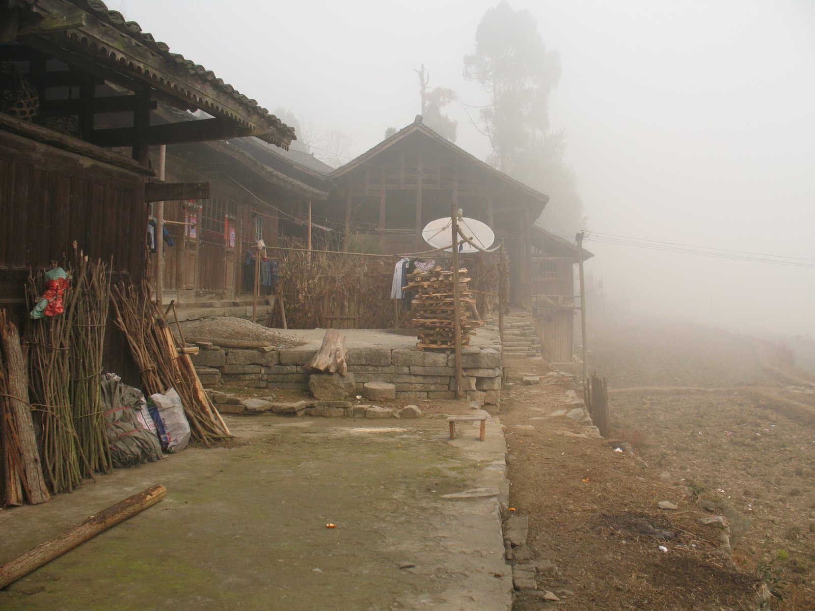 A foggy village scene with traditional buildings and a dirt path