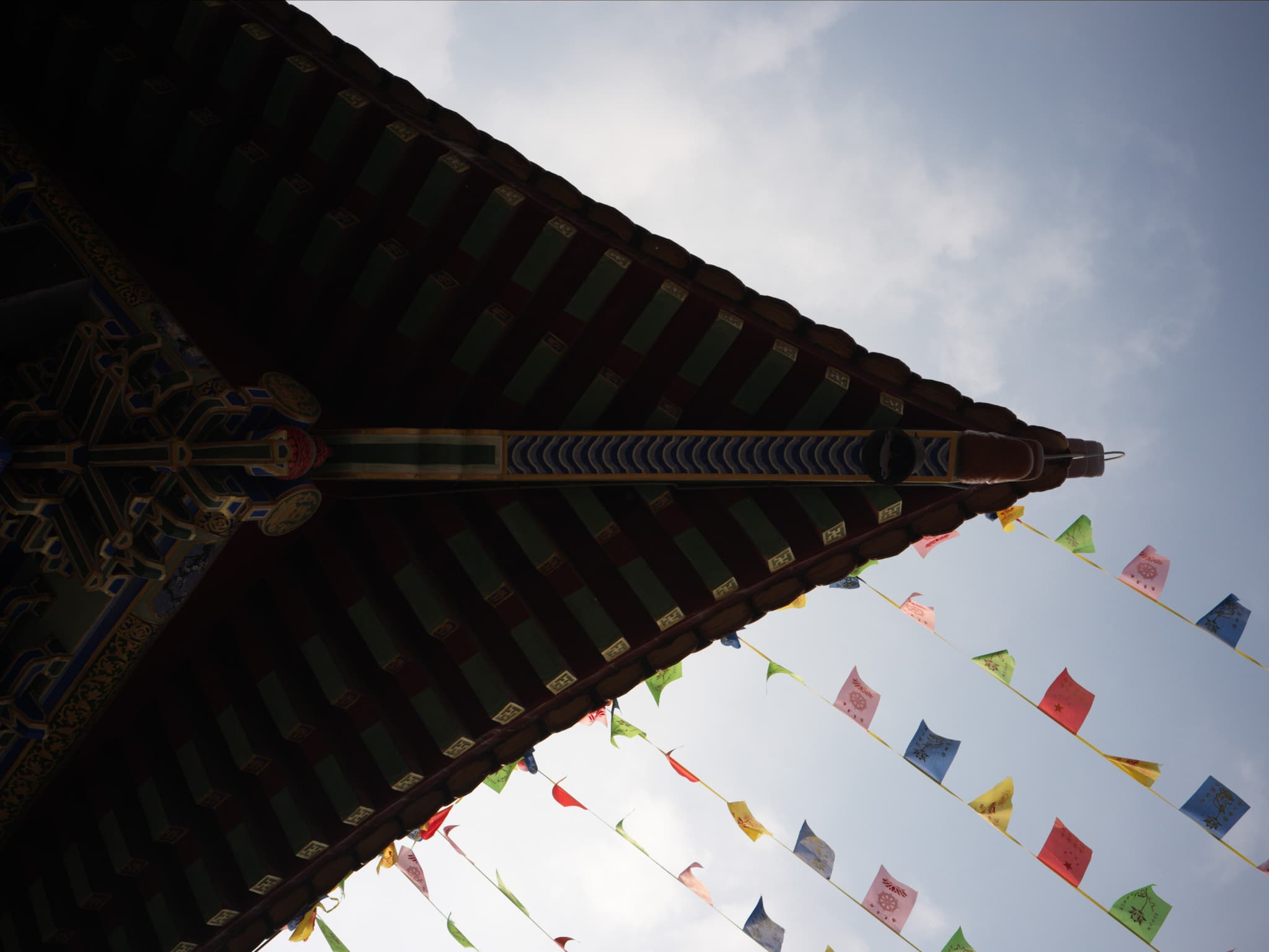 Colorful prayer flags hang below the eave of an Asian-style roof