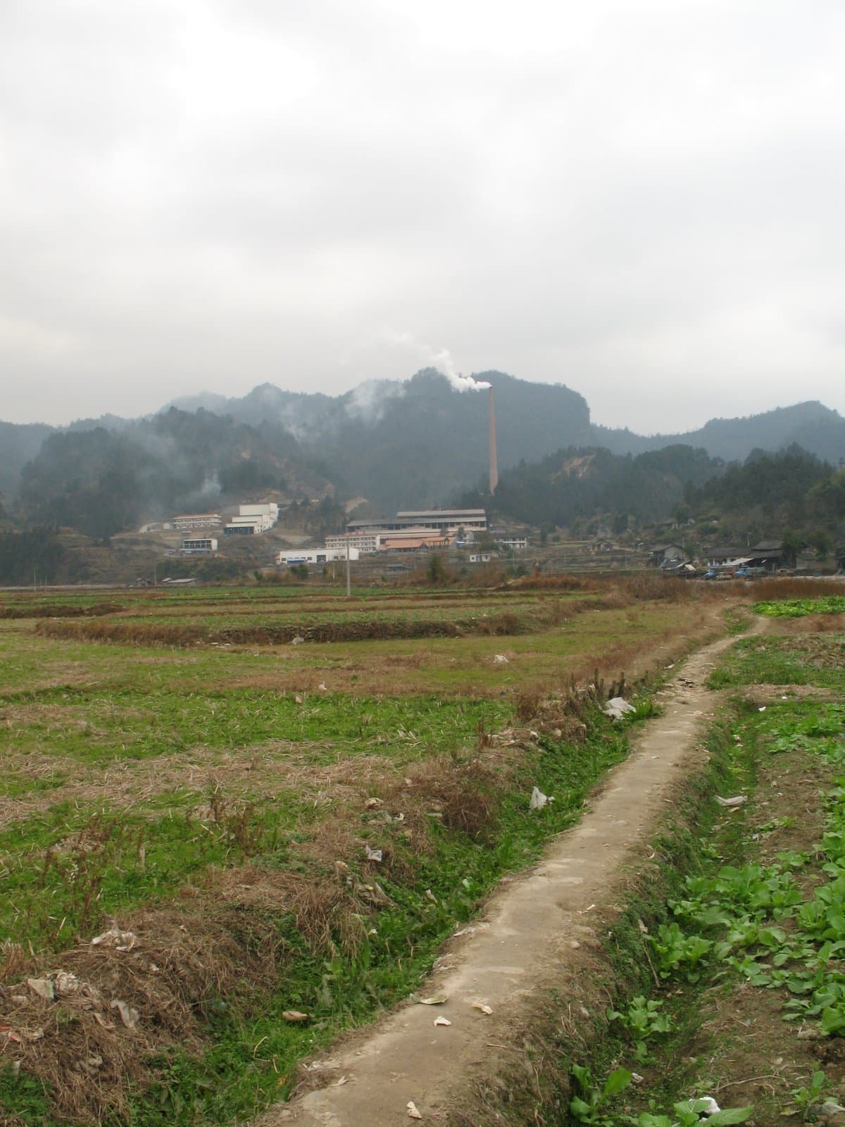 Dirt path leading to a village with mountains in the background