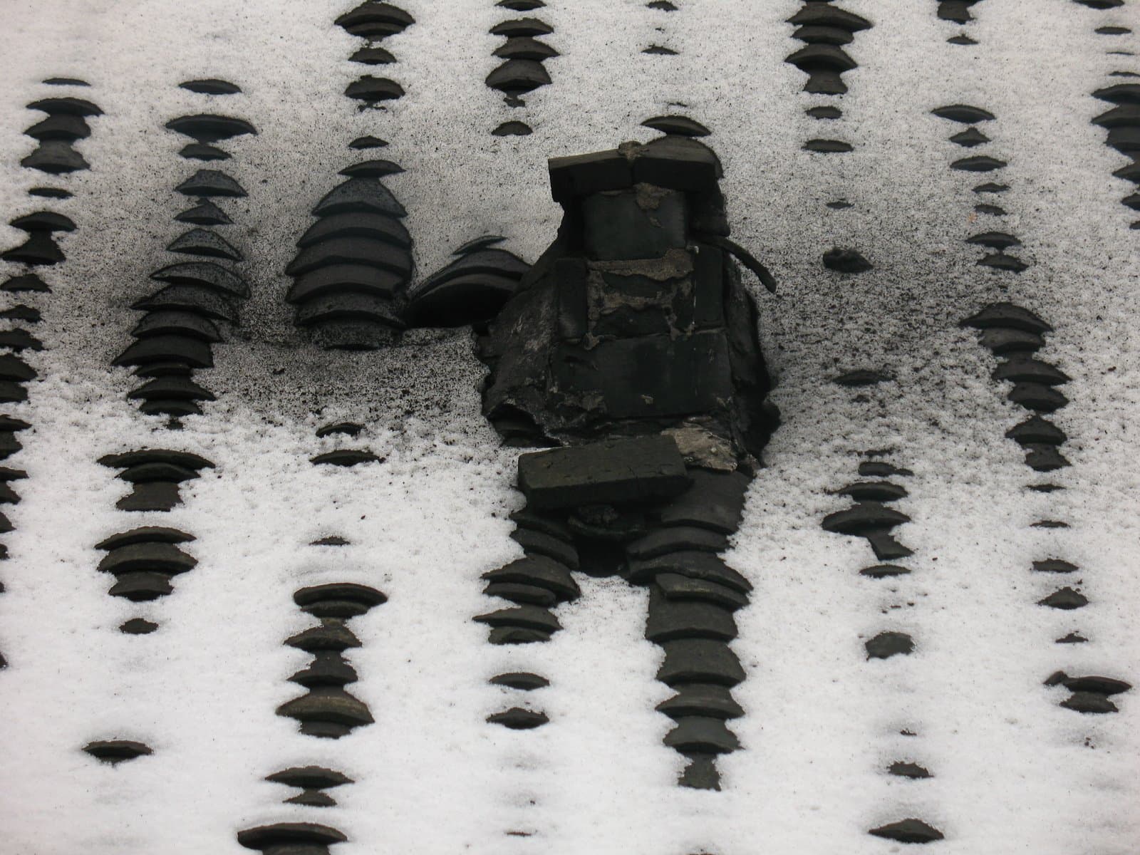 A cluster of icicles hanging from a surface covered in snow and ice