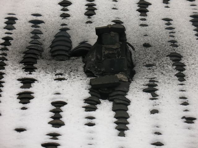 A cluster of icicles hanging from a surface covered in snow and ice