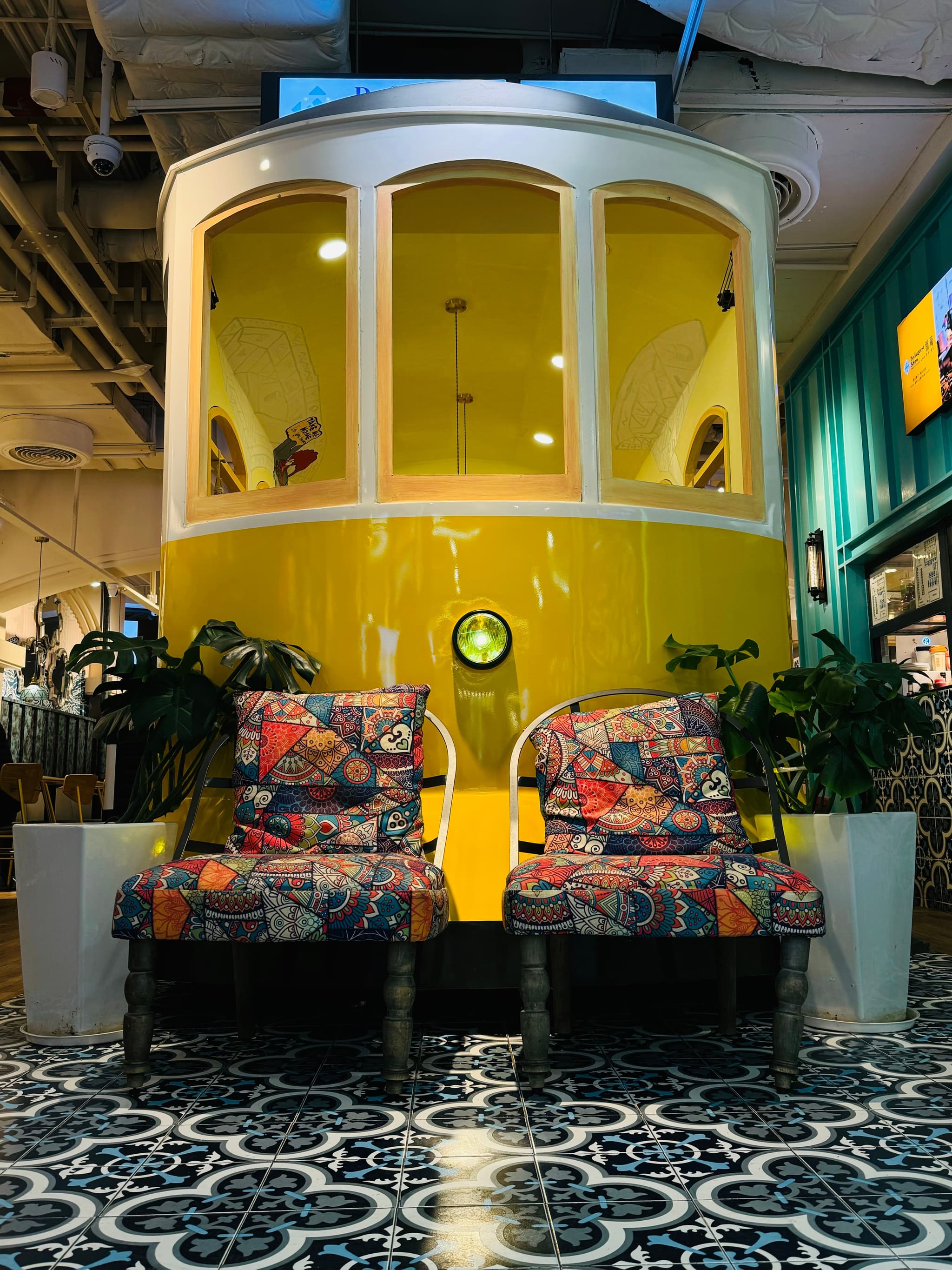 a yellow and white booth with glass windows and patterned chairs