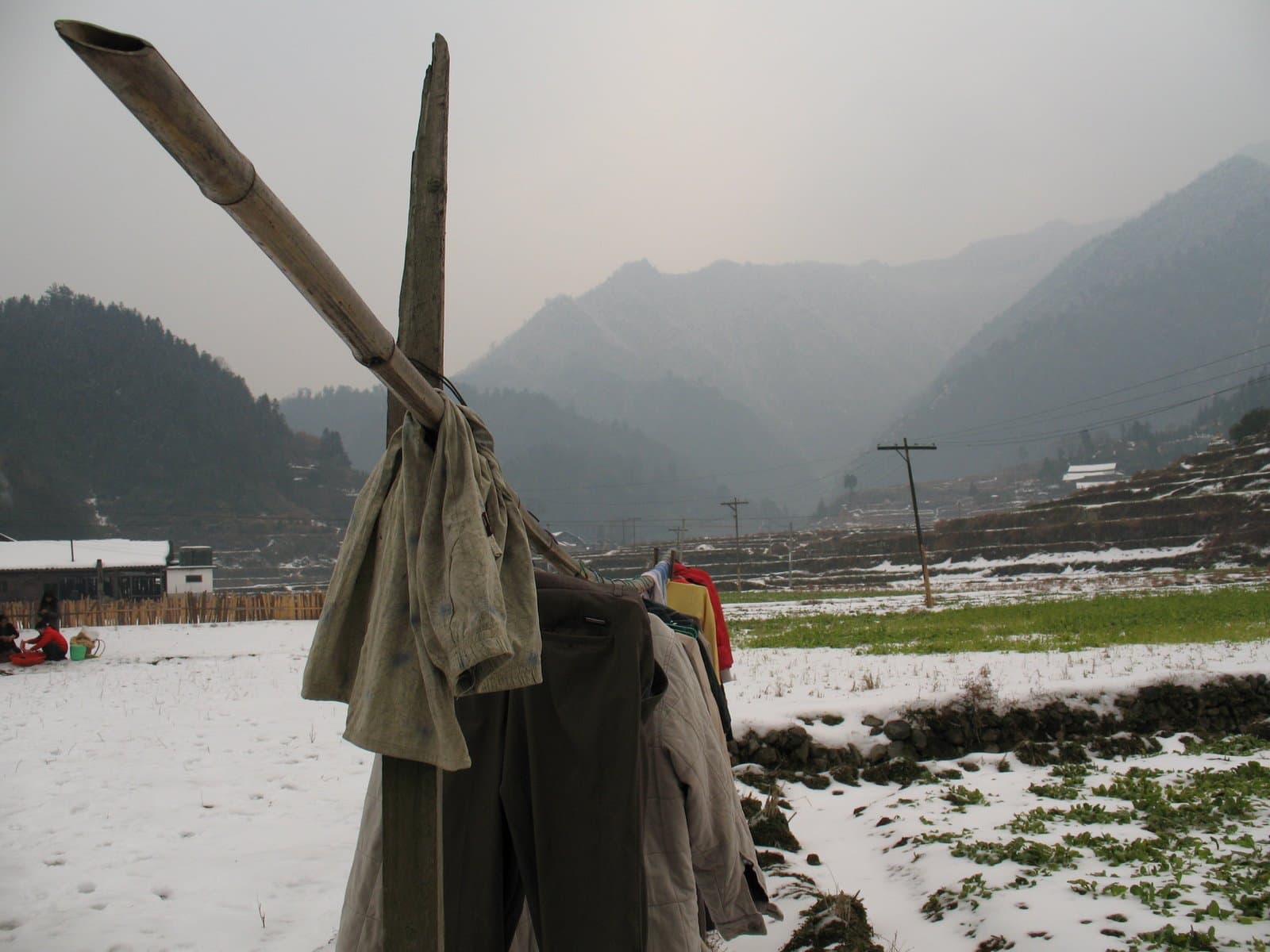 Clothes hanging on a line in a snowy field with mountains in the background