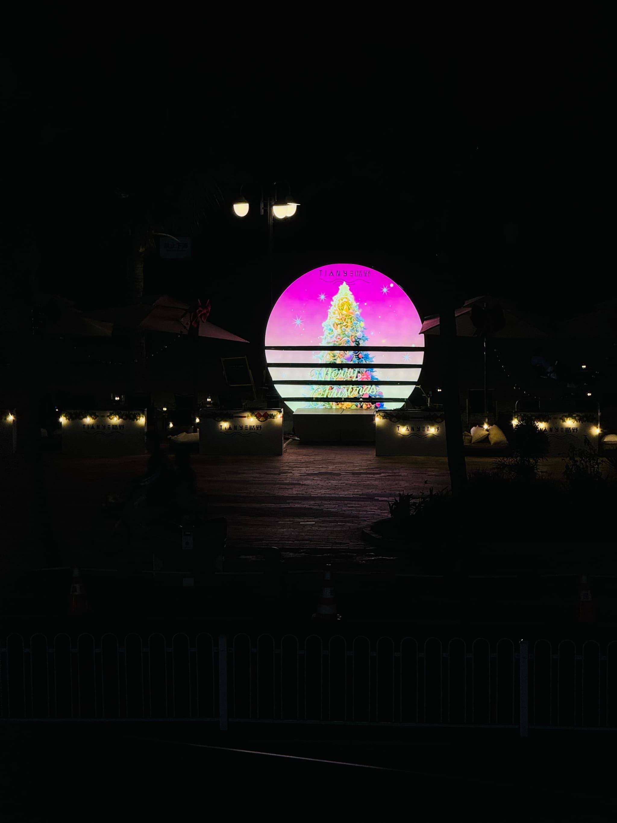 a large pink and green circular light with horizontal lines in front of it and yellow lights on the ground around it
