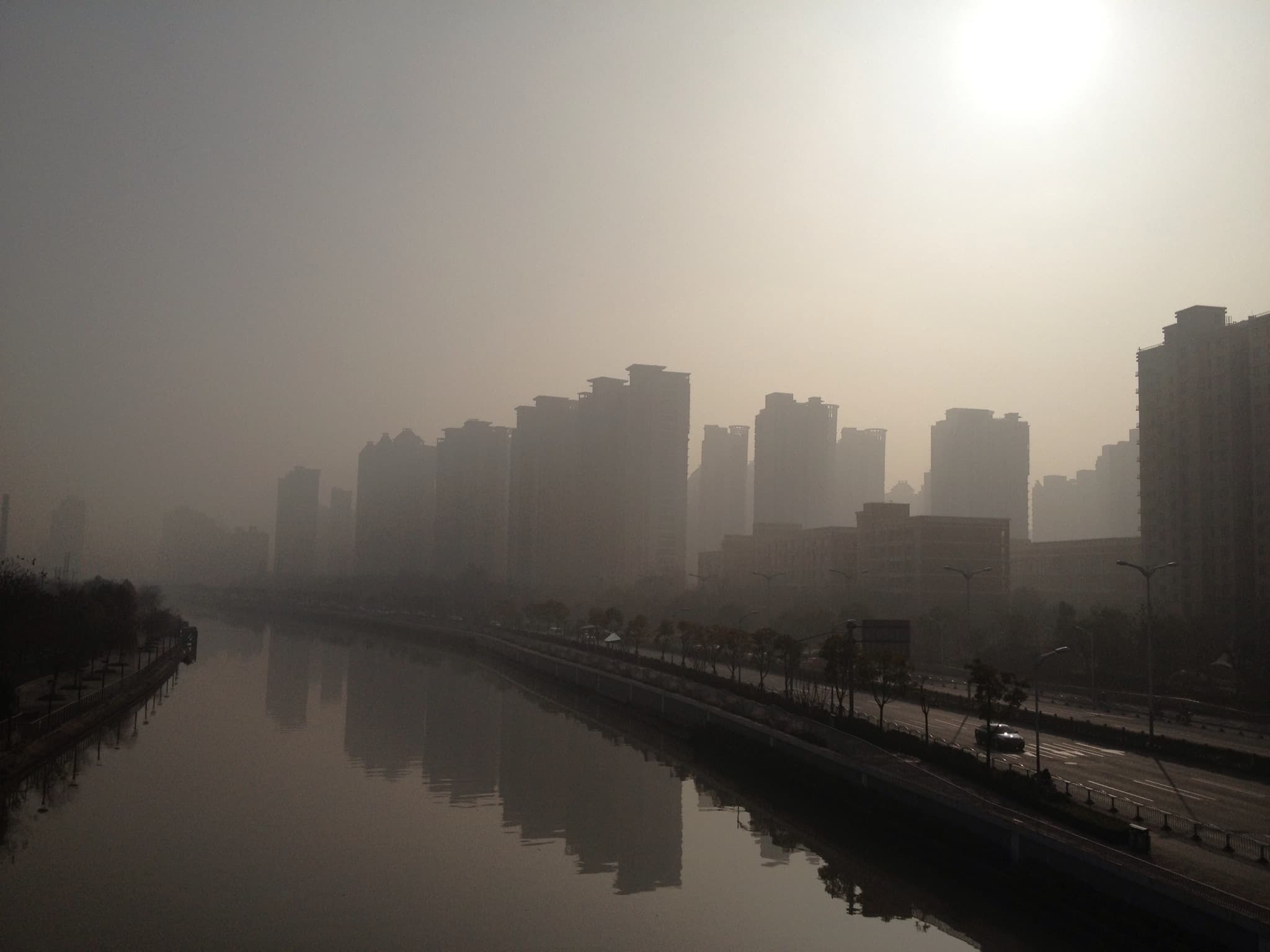 A foggy cityscape reflected in a still body of water