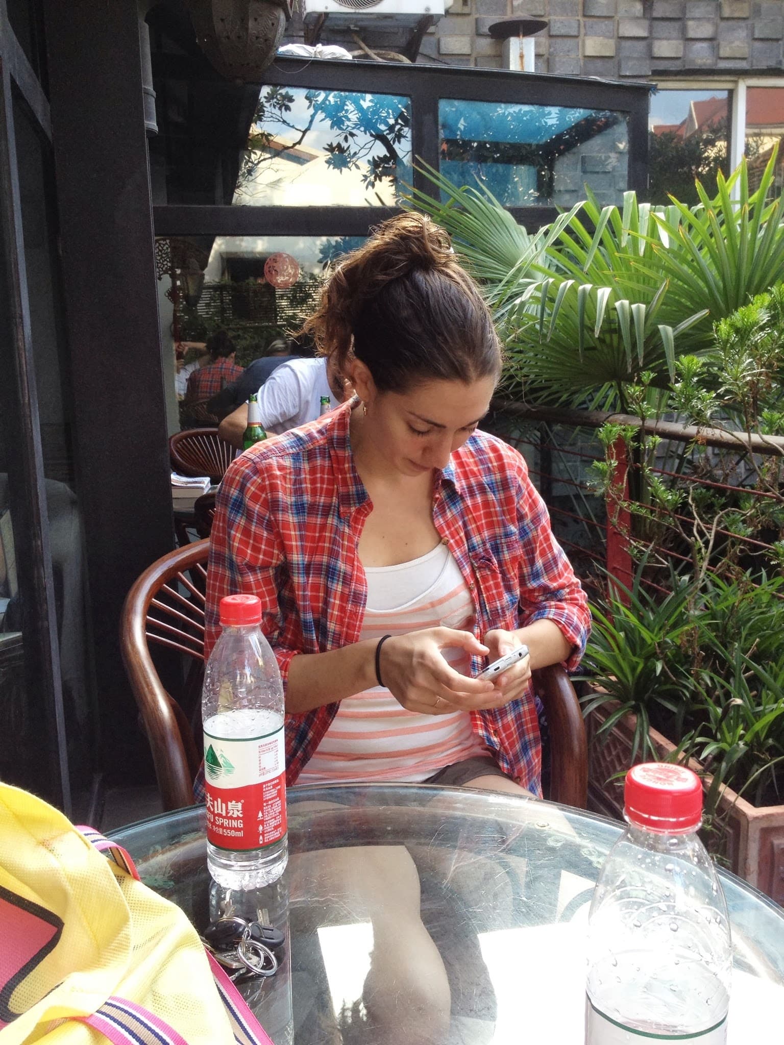 Woman sitting at outdoor table, looking at phone