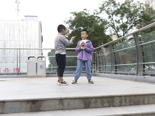 A woman and child on a bridge with a cityscape and trees in the background