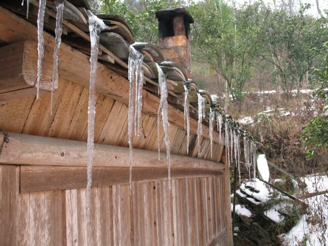 icicles hanging from the edge of a wooden building's roof
