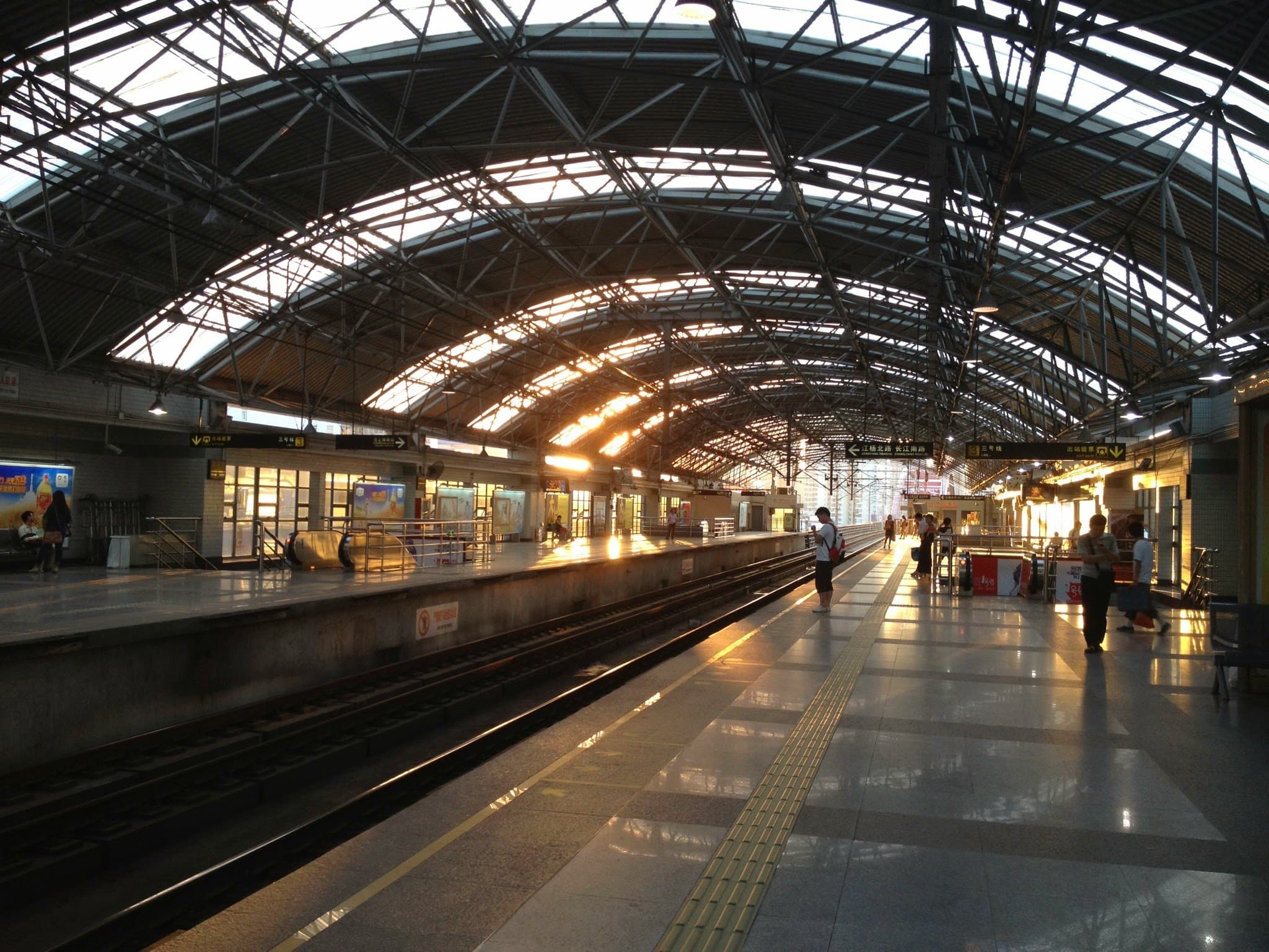 An empty train station platform with a curved roof and tracks