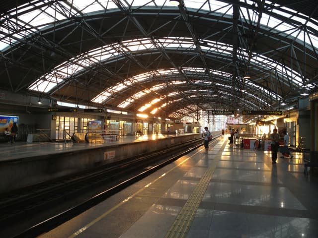 An empty train station platform with a curved roof and tracks