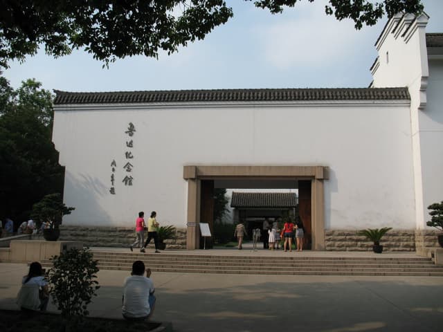 People walking through the entrance of a white building with Chinese characters on the side