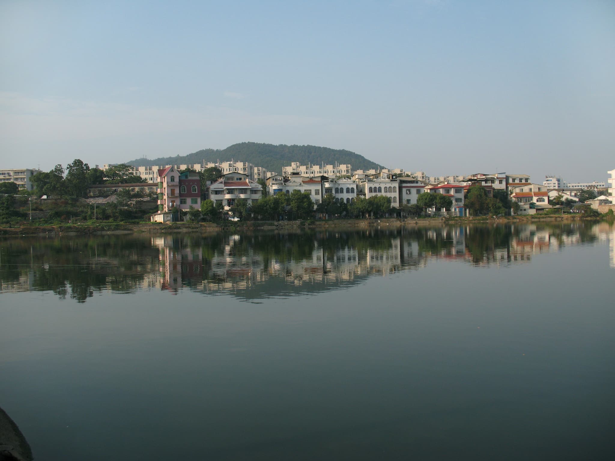 A cityscape with buildings reflected in a calm lake
