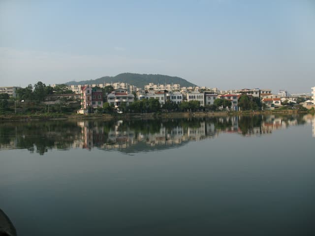 A cityscape with buildings reflected in a calm lake