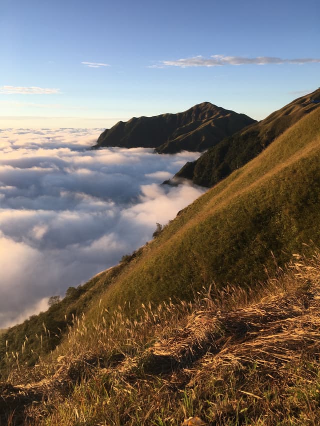 Mountainous landscape with clouds below and blue sky above