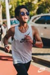A man jogging on a sidewalk wearing athletic gear