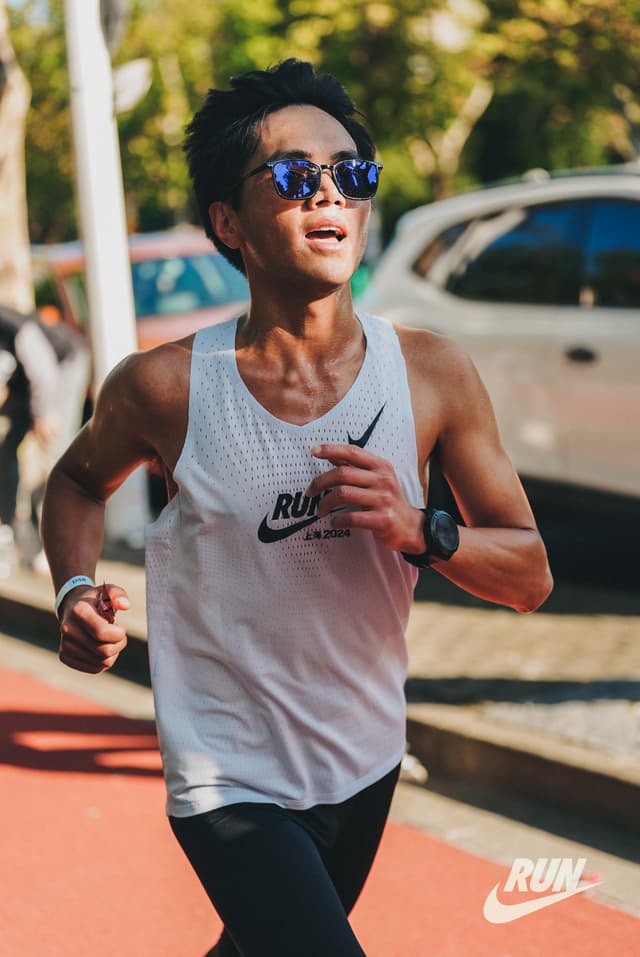A man jogging on a sidewalk wearing athletic gear
