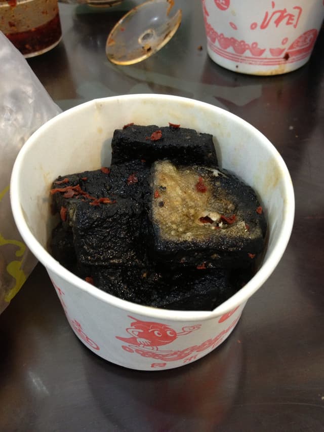 A paper cup containing Changsha Stinky Tofu