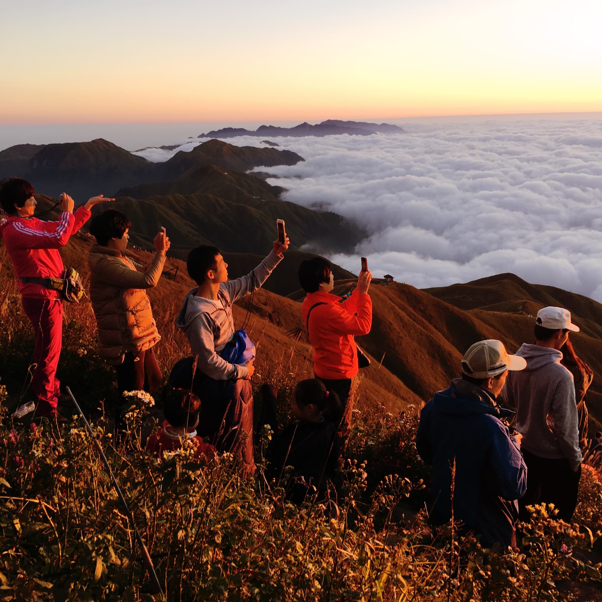 People standing on wugong mountain peak overlooking clouds at sunrise or sunset